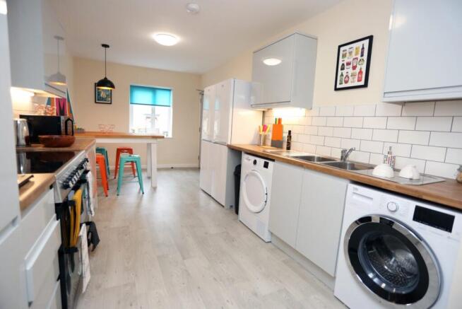 Bright modern kitchen with white cabinets, wood...