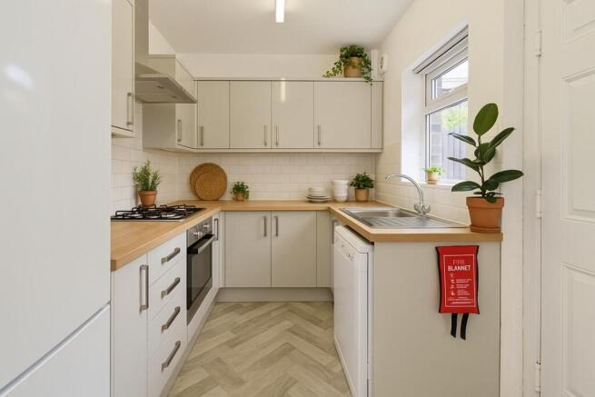 Bright, modern galley kitchen with light wood w...