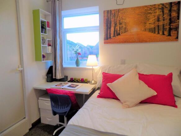 Bright, neatly arranged single bedroom with a c...