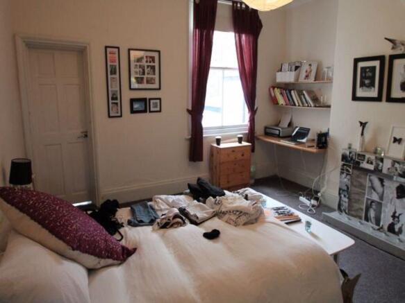 A well-lit bedroom featuring a cozy double bed ...