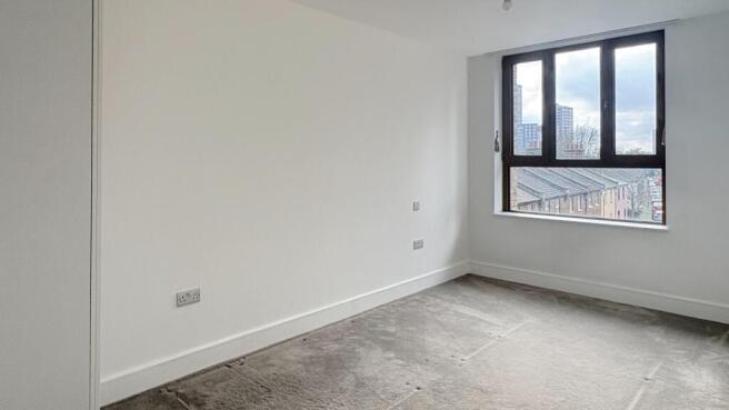 Bright, neutral bedroom with a large window off...