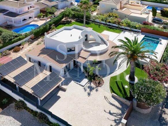 Aerial view of 4-bedroom detached villa in Carvoeiro featuring solar panels, heated pool, and rooftop terrace.