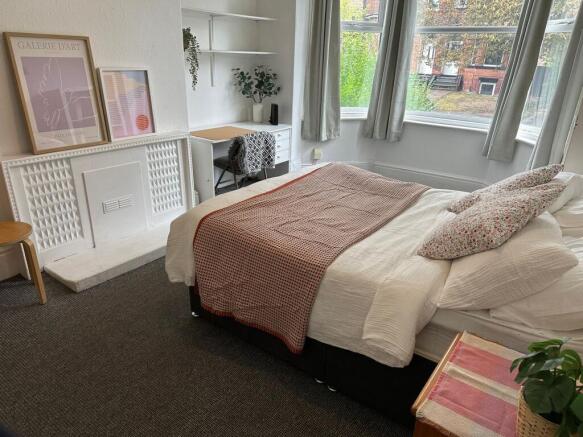 A bright and welcoming bedroom featuring a comf...