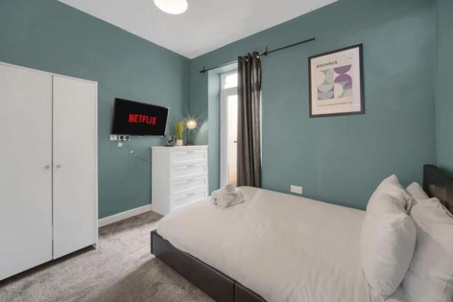Stylish modern bedroom with wall-mounted TV...