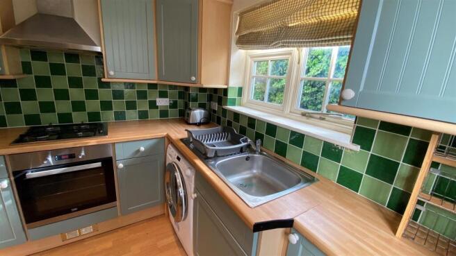Charming kitchen with vibrant green tiled splas...