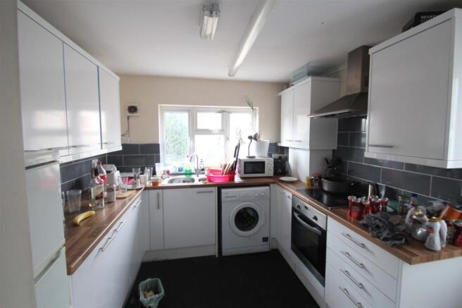 Bright galley kitchen with white cabinets, wood...