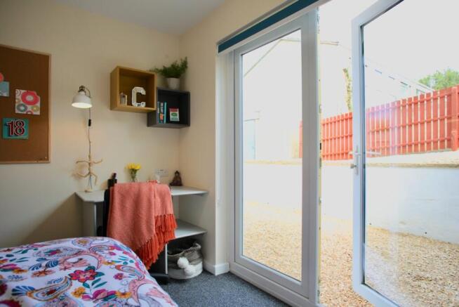 Bright, neatly styled bedroom with sliding glas...