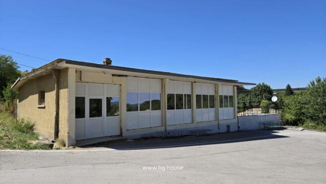 Exterior view of the commercial building showing large white-framed windows and entrance door