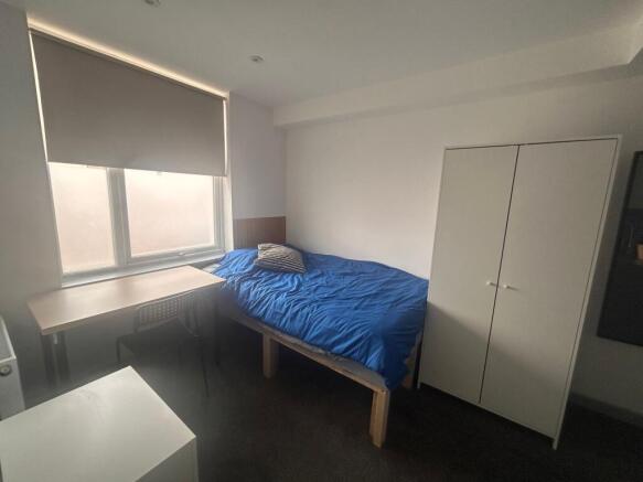 Bright, simply furnished room with desk and bed...