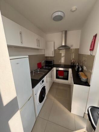 Bright, modern galley kitchen with white cabine...