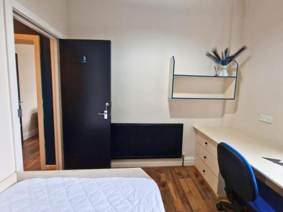 Neat single bedroom with a built-in desk and sh...