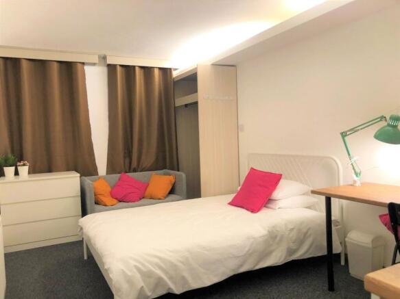 A cozy and tidy single bedroom featuring a comf...