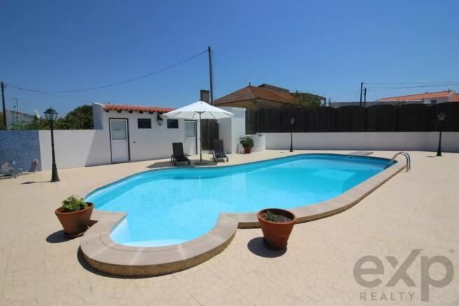 A clear swimming pool with loungers and an umbrell