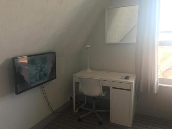 Bright workspace with wall-mounted TV and desk...