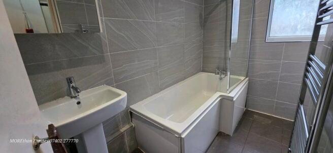Modern bathroom with sleek grey tiling and bath...