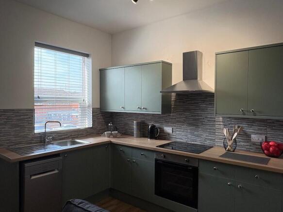 Modern fitted kitchen with pale green cabinetry...