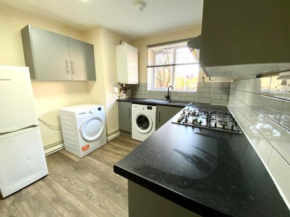 Modern galley kitchen with dark worktops, grey ...