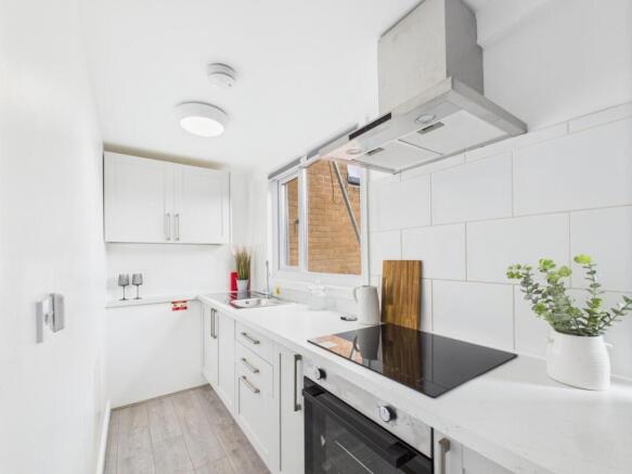 Bright, modern galley kitchen with white cabine...