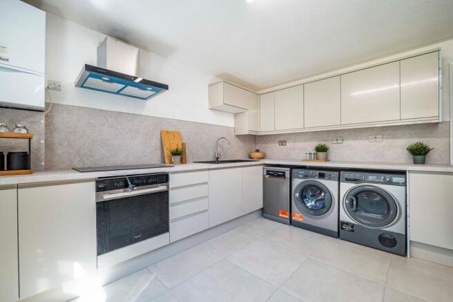Modern, well-lit kitchen with sleek white cabin...