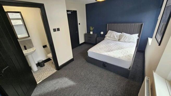 A clean and well-lit bedroom featuring a comfor...