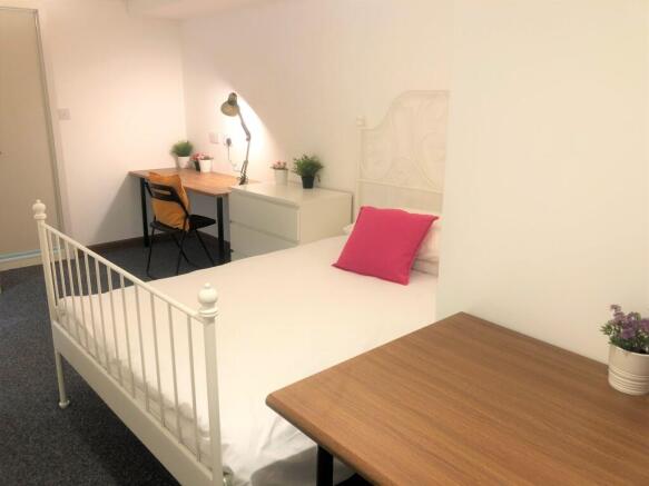 A neat and cozy single bedroom featuring a whit...