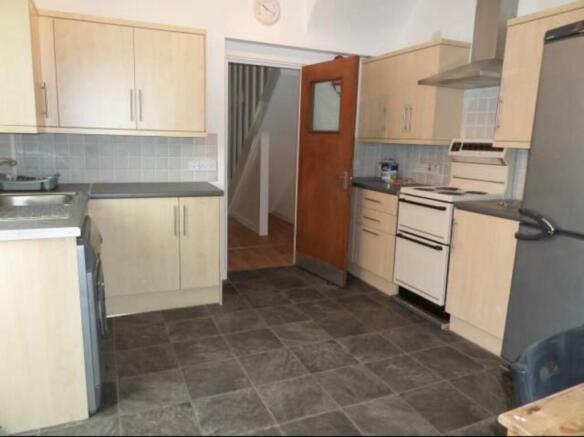 Well-equipped kitchen with modern light-wood ca...