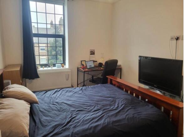 Bright bedroom with bed, desk and TV...