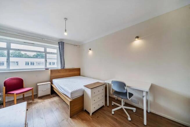 Bright furnished bedroom with desk and storage...