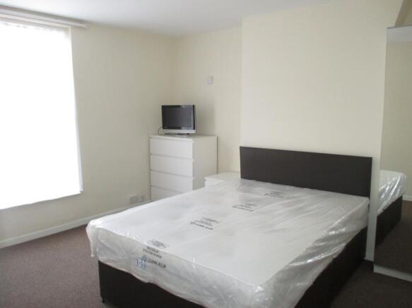Bright double bedroom with a large window, fres...