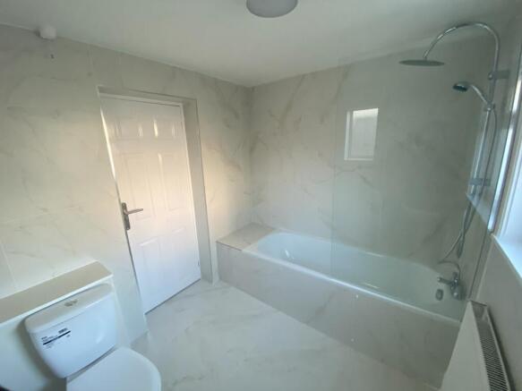 A clean and modern bathroom featuring a bath an...