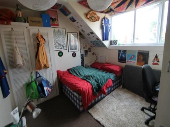 A cozy bedroom featuring a single bed with a co...