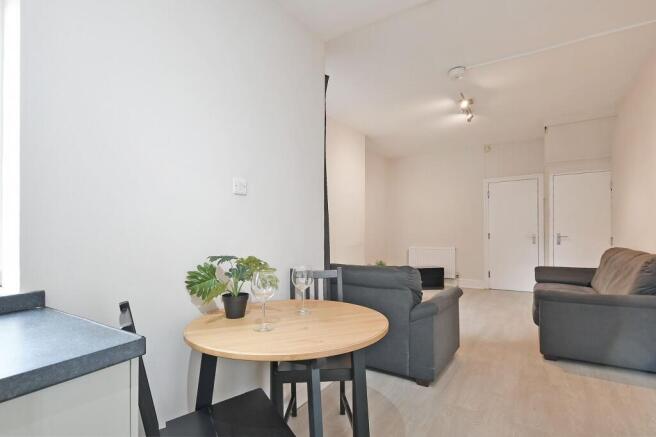 Bright, neutral living area with a small dining...