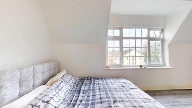 Bright bedroom with a large window and comfy be...