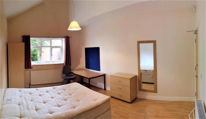 Bright bedroom with vaulted ceiling and desk ar...
