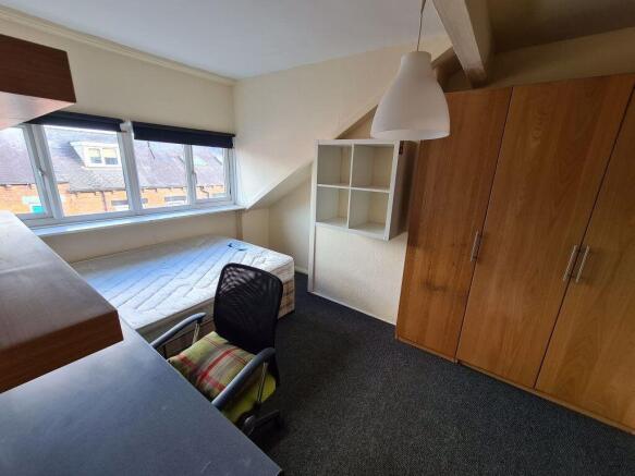 A cozy single bedroom featuring a large window ...