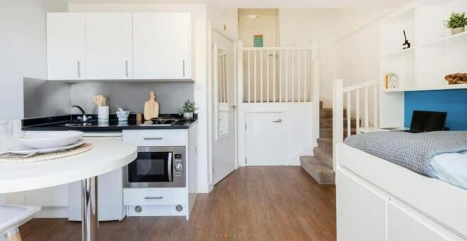 Modern studio kitchen with sleek white cabinets...