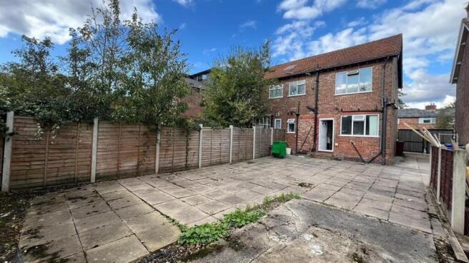 Paved rear outdoor space with mature trees, sec...