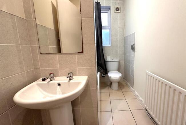 Bright tiled bathroom with a pedestal sink, mir...