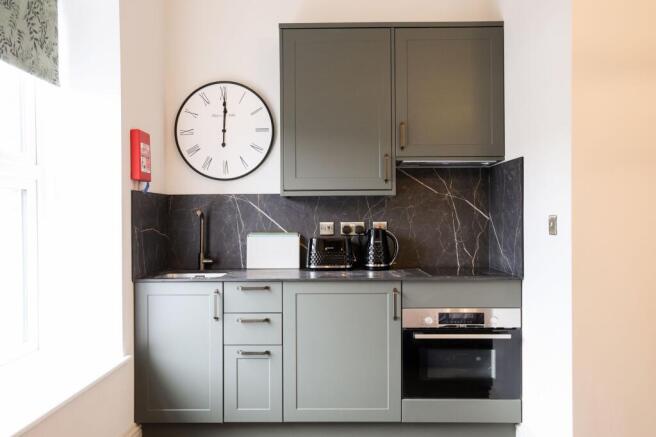 Modern kitchen with sleek sage units and marble...