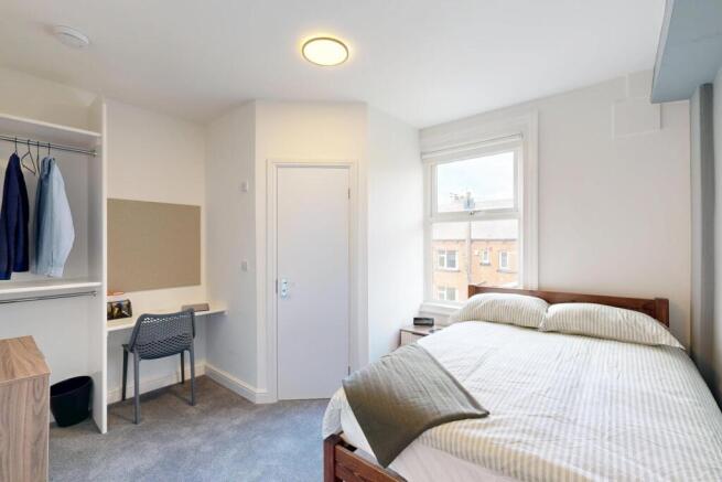 A bright and tidy student bedroom featuring a c...