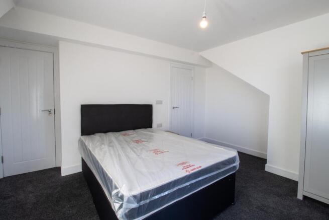 A spacious double bedroom featuring a large bed...