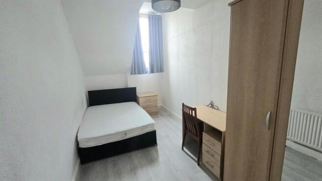Bright, simply furnished bedroom with bed and d...