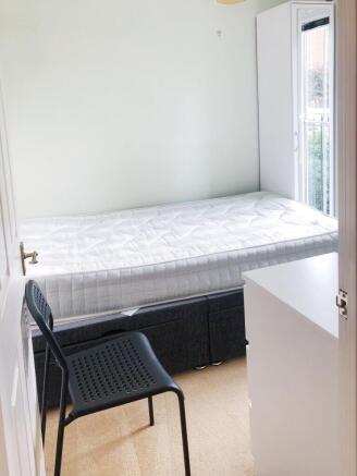 Bright, simply furnished bedroom with a comfort...