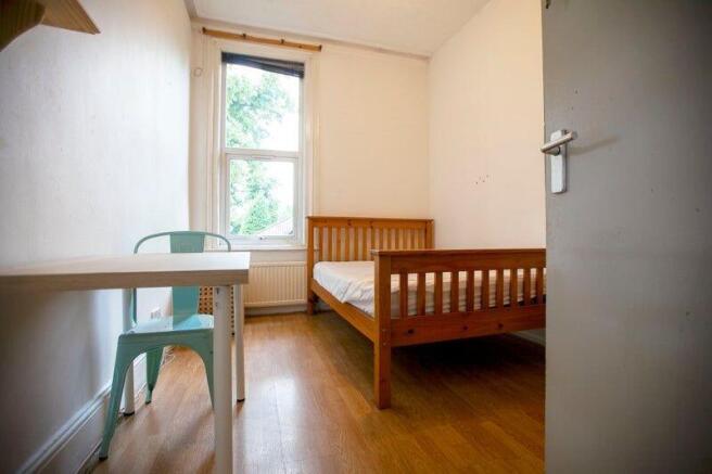 Simple bedroom with bed and desk by window...