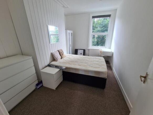 A tidy bedroom featuring a double bed with a sm...