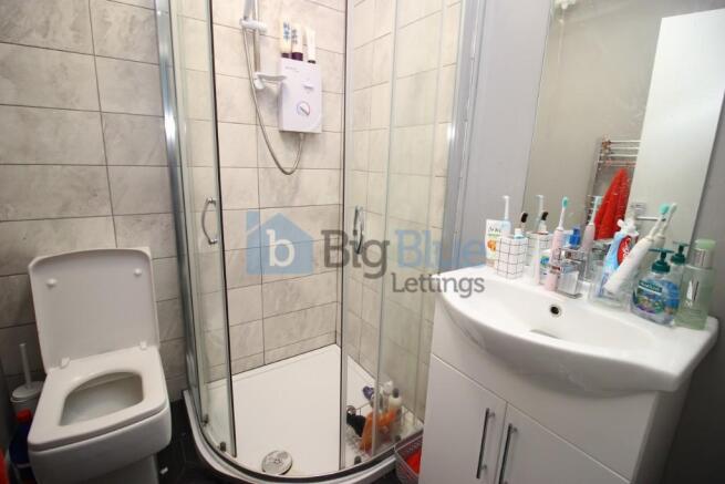 A modern bathroom suite featuring a curved glas...