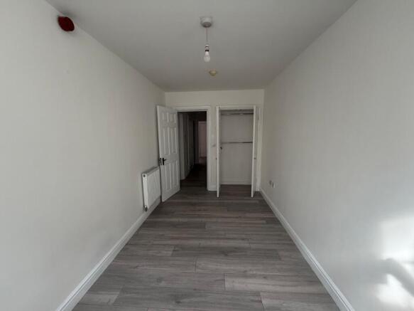 Long, freshly painted single bedroom with light...