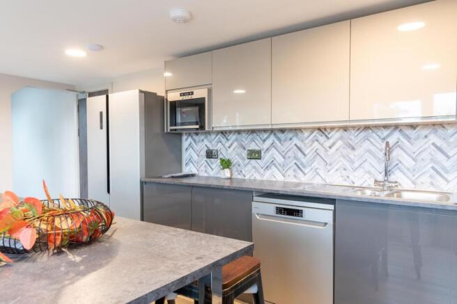 Modern kitchen with glossy grey cabinets, stain...