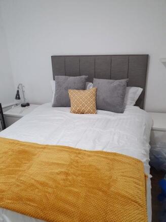 Bright, neatly made double bedroom with a conte...