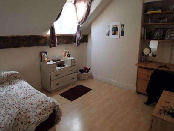 A cozy single bedroom featuring a bed with flor...